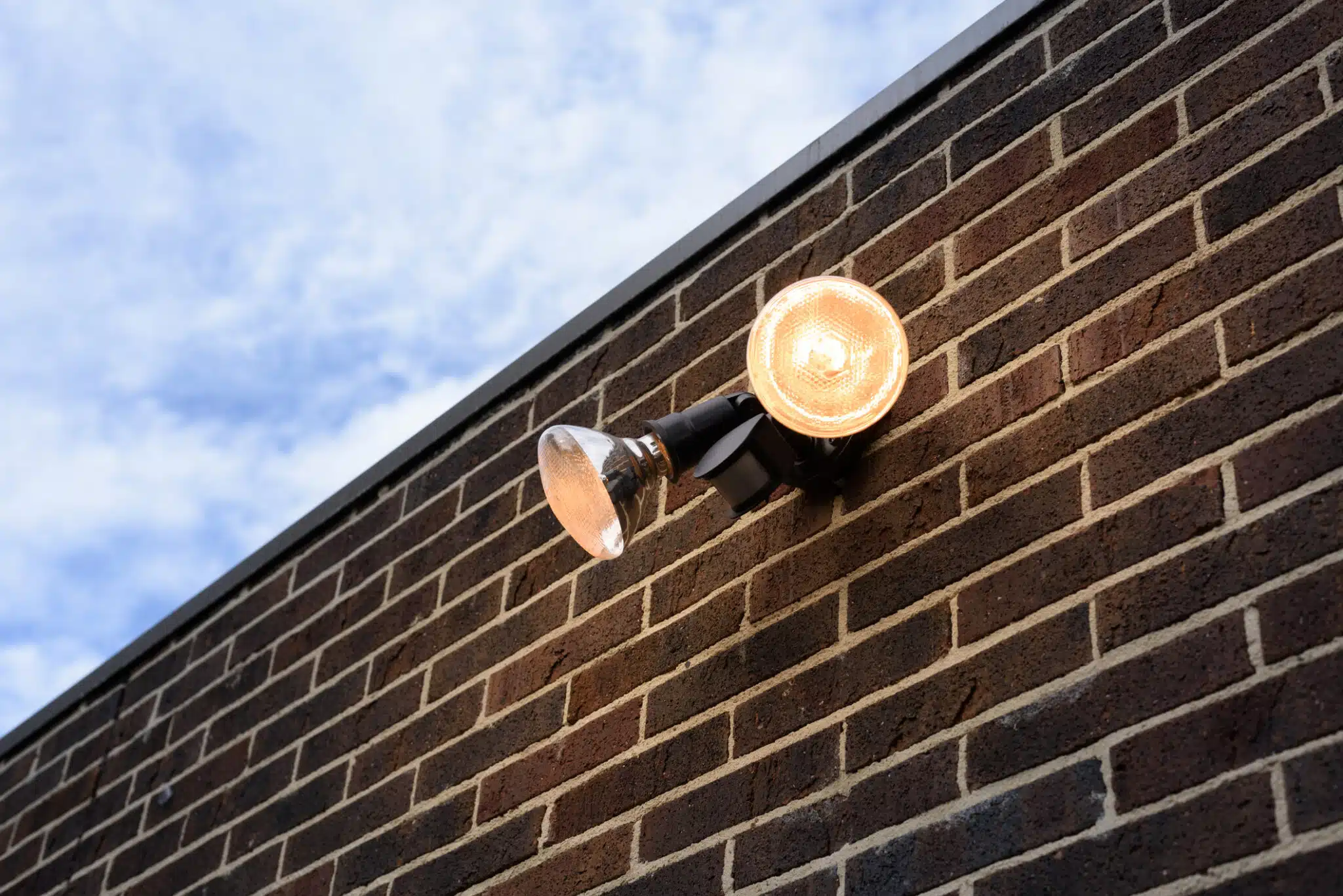 Automated External Lighting Systems, Flood light on external brick wall daytime look up.